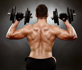 Fototapeta na wymiar Athletic young man working with heavy dumbbells