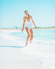 Smiling young woman playing with waves on beach