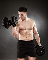 Fototapeta na wymiar Athletic man working out with heavy dumbbells