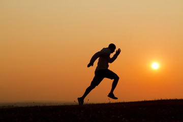 Fototapeta na wymiar Sunset silhouette of a man running uphill