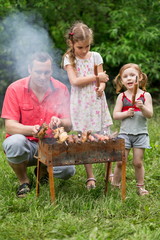 A family of three making barbecue on the grill