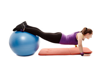 Athletic woman doing pushups with legs on the ball