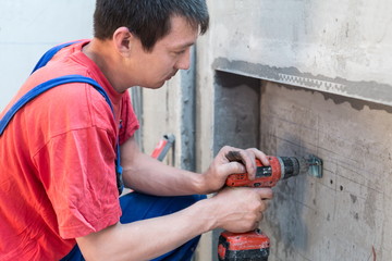 Worker have fixes the fastening in niche for radiators