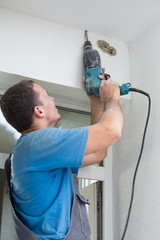 Worker makes a hole in the ceiling using a drill