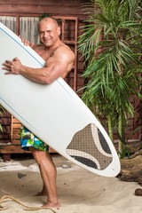 muscular man on a sandy beach with a surfboard