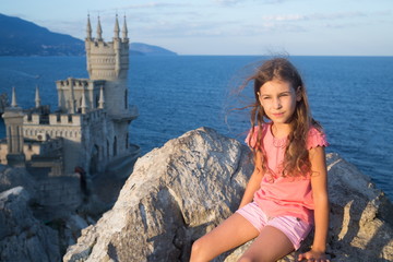 Fototapeta na wymiar Little girl on the nature with old castle and the sea