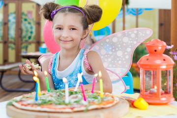 Girl in fairy costume with a piece of pizza in hand