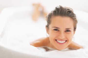 Obraz na płótnie Canvas Portrait of smiling young woman laying in bathtub