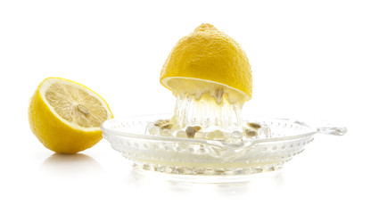 Glass citrus squeezer with lemons and juice on a white backgroun