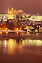 Night colorful snowy Prague gothic Castle with Charles Bridge