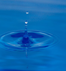 a drop of water falling in blue water