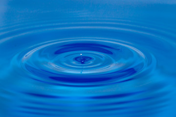 a drop of water falling in blue water