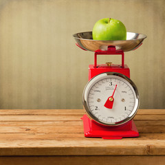 Apple on vintage scale on wooden table
