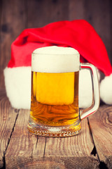 mug of beer with Santa's hat on wooden background