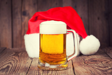 Obraz na płótnie Canvas mug of beer with Santa's hat on wooden background