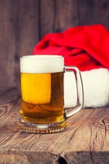 mug of beer with Santa's hat on wooden background