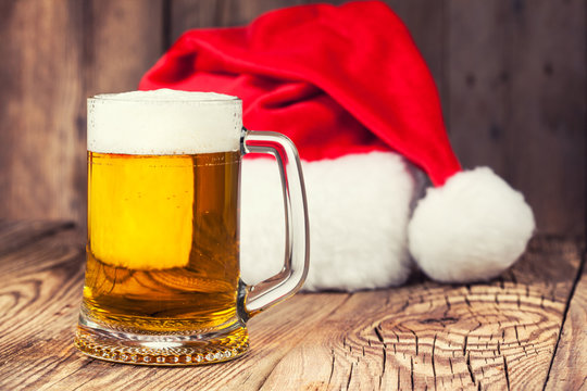 mug of beer with Santa's hat on wooden background