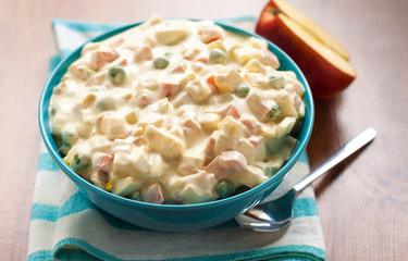 Vegetable salad with mayonnaise sauce with an apple on the table