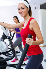 Young people with elliptic machine in the gym