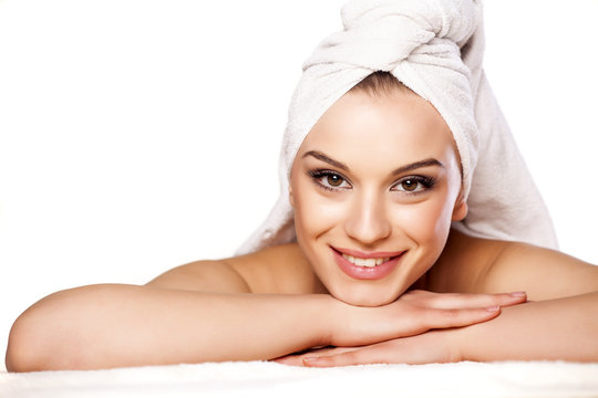 smiling beautiful girl with a towel on her head posing on white