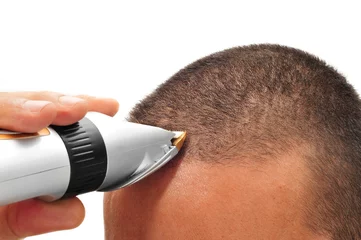 Cercles muraux Salon de coiffure homme se coupant les cheveux avec une tondeuse à cheveux électrique