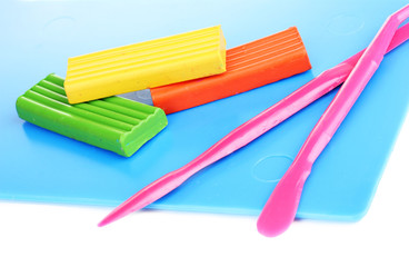 Obraz premium Colorful modeling clay and sculpting tools for creative arts and crafts activities on a blue mat, the items are isolated on a clean white background