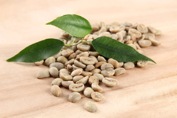 Green coffee beans and leaves on wooden background