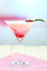 Raspberry milk dessert in cocktail glass, on light background