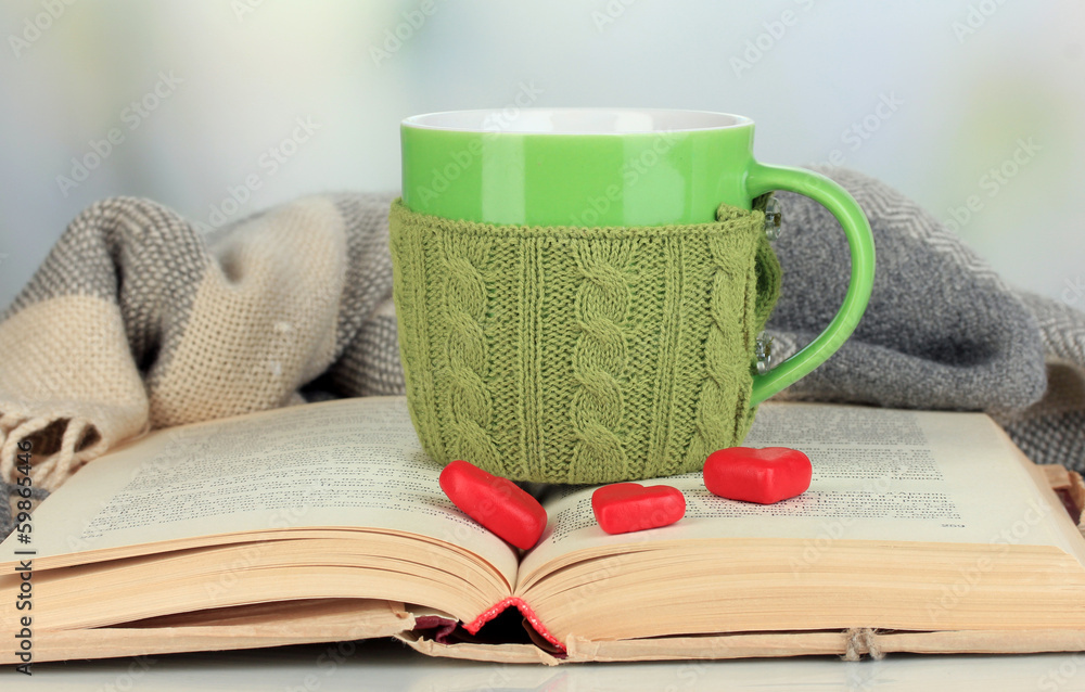 Aufkleber cup with knitted thing on it and open book close up