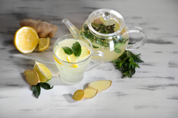 Kettle and cup of tea with ginger on wooden table