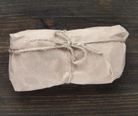Telephone wrapped in brown kraft paper, on wooden background