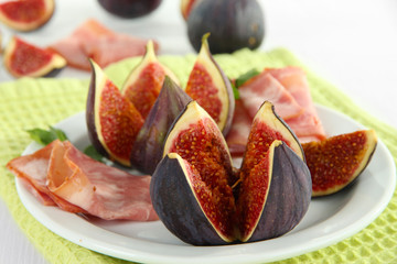 Tasty figs with ham on white wooden table
