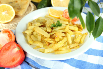 Ruddy fried potatoes on plate on tablecloth close-up