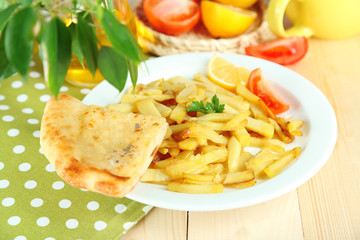 Ruddy fried potatoes on plate on tablecloth close-up