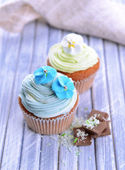 Tasty cupcakes with butter cream, on color wooden background