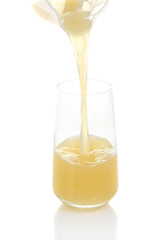 Juice pouring into glass isolated on white