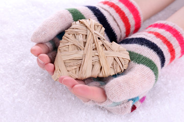 Female hands in mittens with heart on snow background