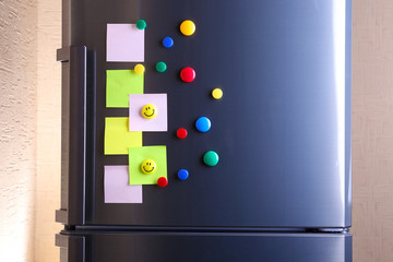 Empty paper sheets and colorful magnets on fridge door
