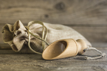 Fototapeta na wymiar burlap sack and wooden scoop on a wooden background