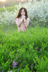 Naklejka na ściany i meble Beautiful girl in a flowered garden topless
