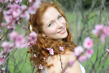 beautiful red-haired girl among the flowering trees