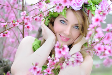 Obraz premium Beautiful girl in a flowered garden peach