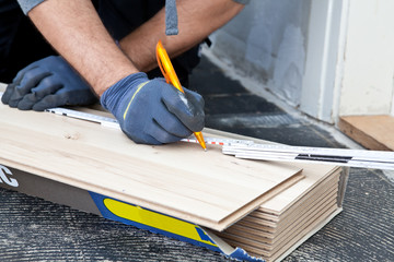 Carpenter measuring new wooden flooring