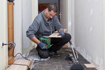Carpenter sanding and cutting new floor boards
