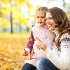 Mother and daughter having fun in the autumn park