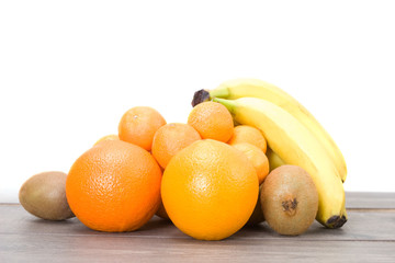 kiwi, bananas, oranges and tangerines on a wooden table