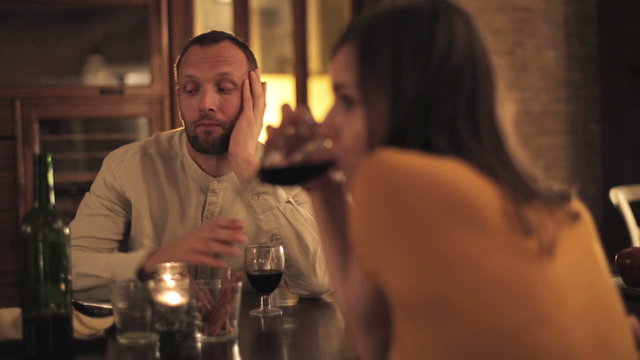 Offended man sitting by the table with boyfriend at home