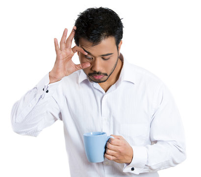 Sleepy business man holding cup of coffee, trying to stay awake