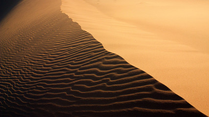 Sand texture with light and shadows and wind-created waves