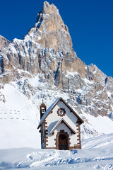 Small church in front of peak in Passo Rolle, Italy